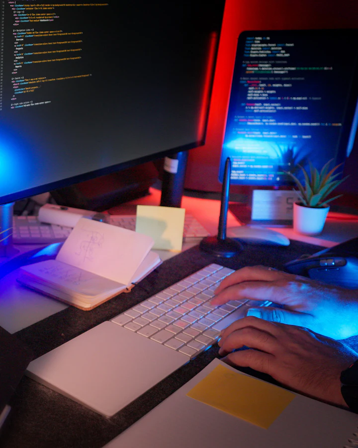 Developer typing at a desk with code on two monitors